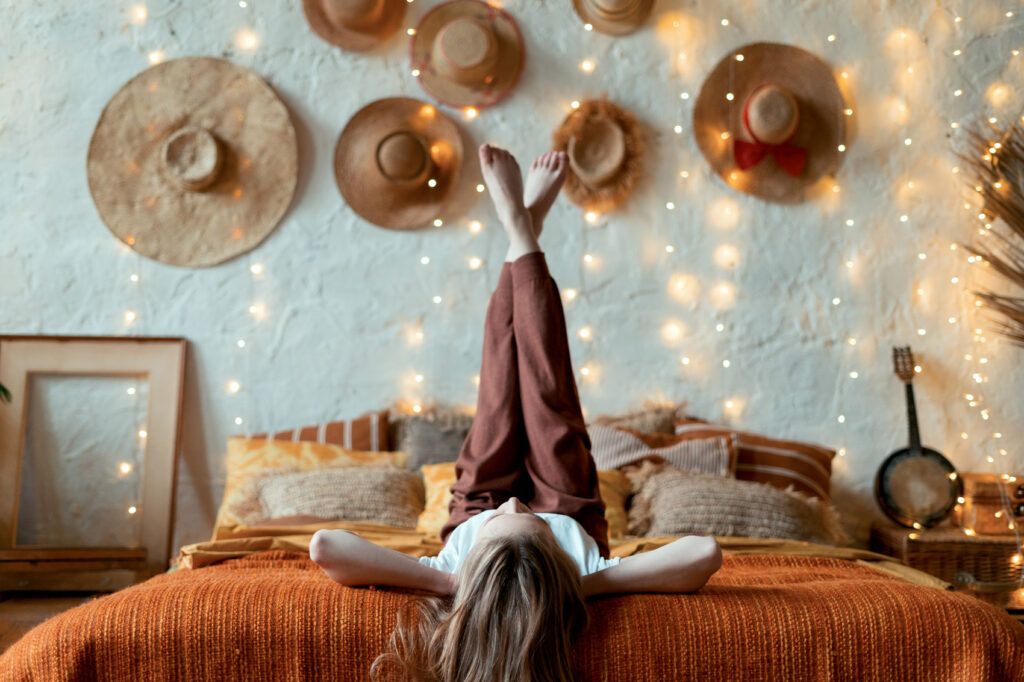 Mujer disfrutando del confort con una decoración de sombreros en la pared - Cómo Elegir el Alojamiento Perfecto para tu Próximo Viaje