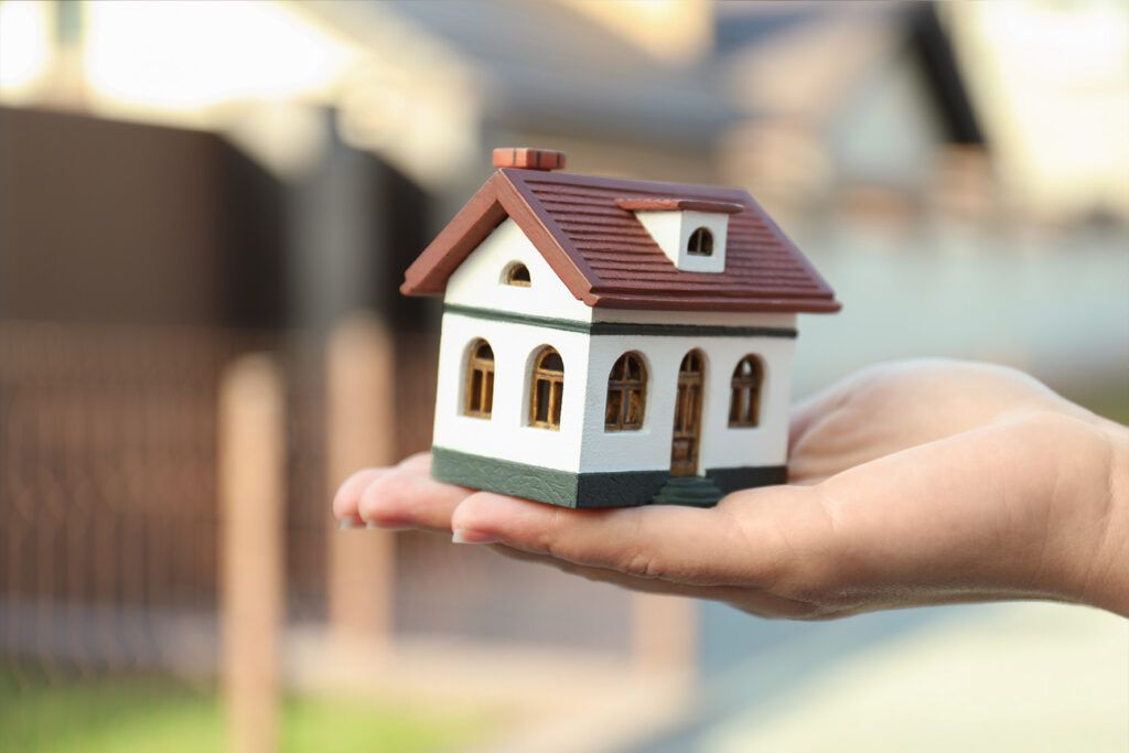Agente inmobiliario con casa modelo en la palma de su mano - Beneficios de reservar directamente